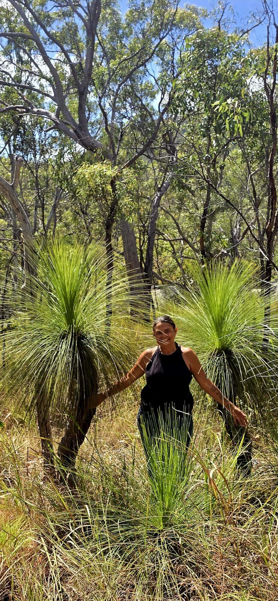 Julie standing among grass trees on Country.