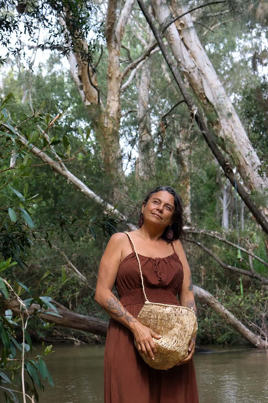 Julie on Country carrying a woven fibre bag.