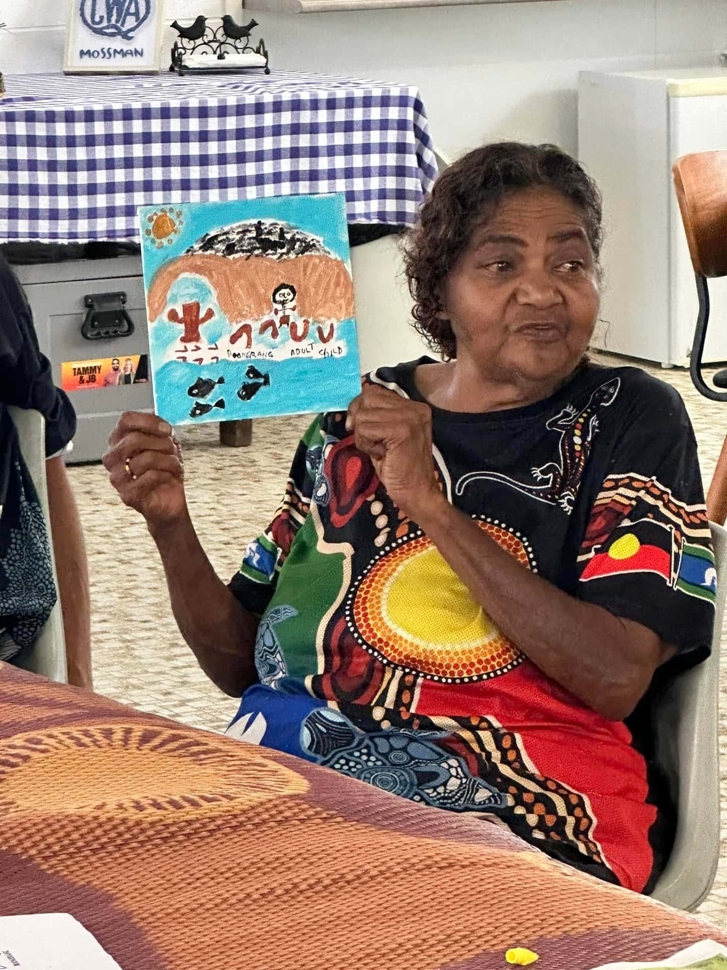 A workshop participant holding up her ochre artwork.