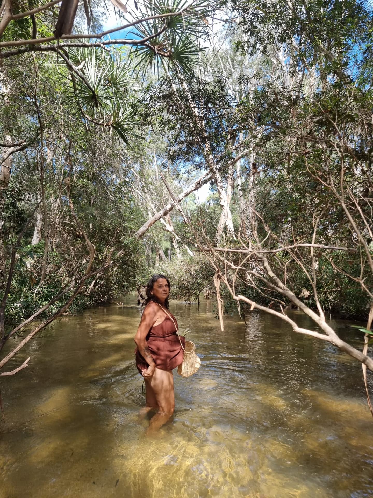 Julie standing in clear creek water on Country.
